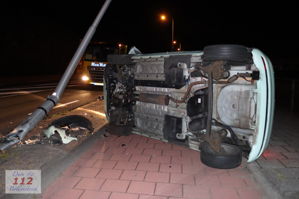 Auto botst tegen paal en belandt op zijkant in Lisse